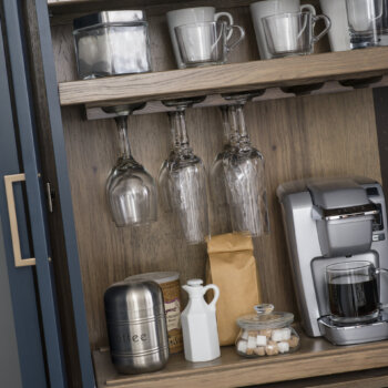 A beverage center larder cabinet with customized internal storage accessories including apothecary drawers, a flat roll-out shelf for a coffee maker or blender, and additional customized shelving.